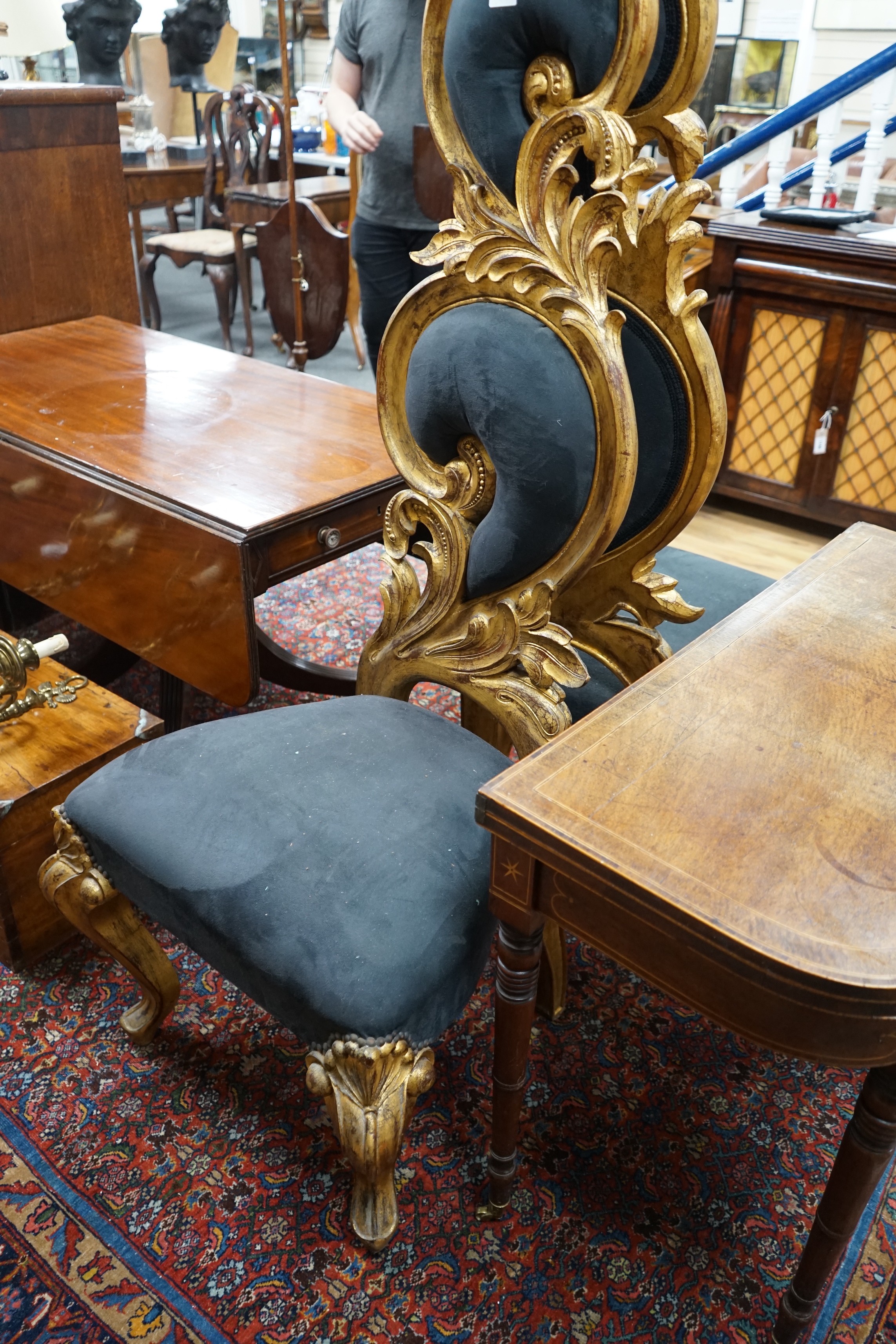 A pair of ornate foliate carved gilt scroll hall chairs with black suede upholstery, height 160cm